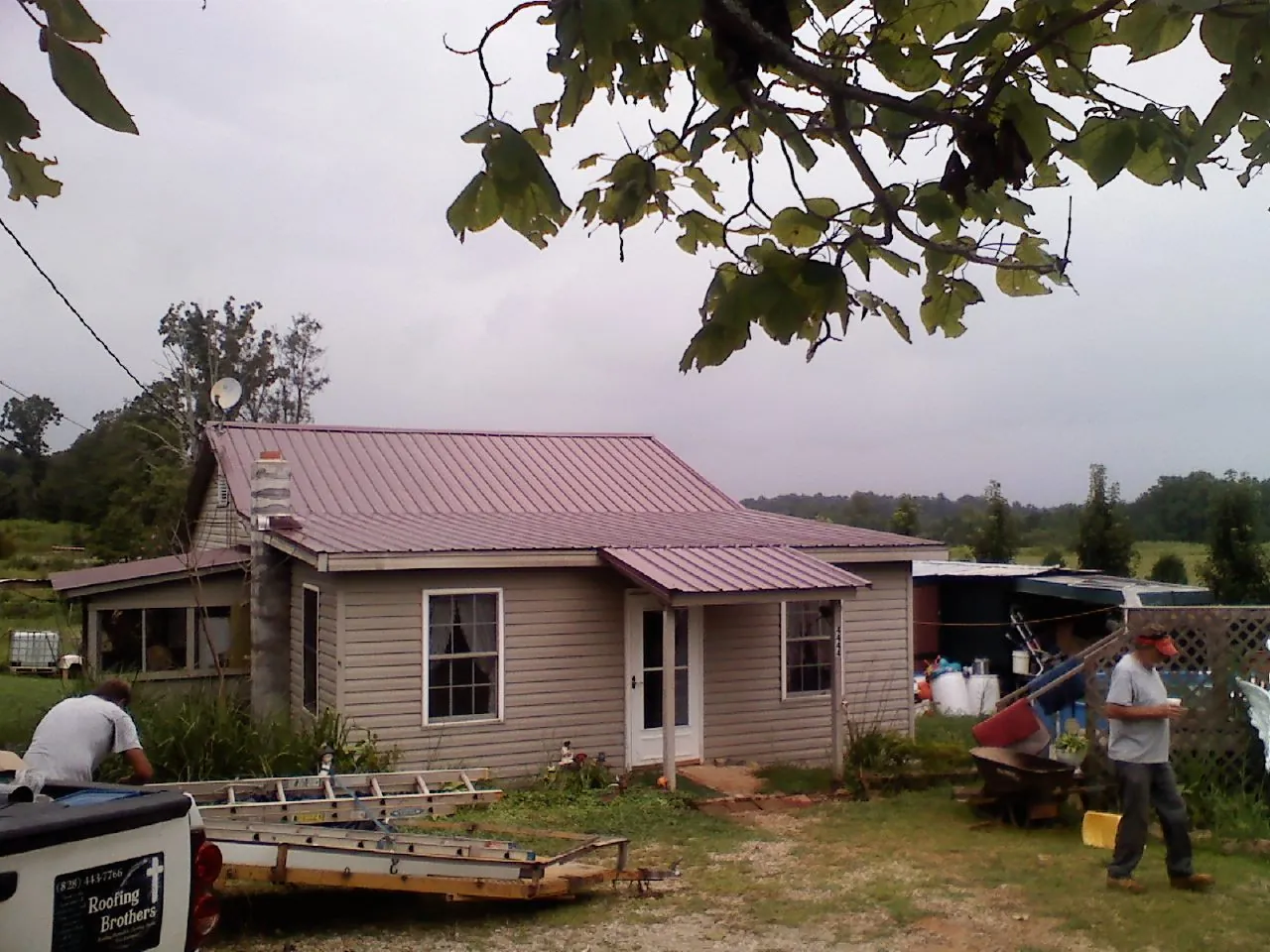 Crew finishing a mauve metal roof on a small farmhouse in Louisville